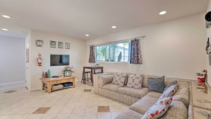 A living room with a sofa, TV, and a small table with decorative items. - 'vegas Oasis' Home w/ Pool & Spa: 7 Miles to Strip (Las Vegas)