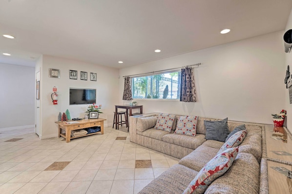 A living room with a sofa, TV, and a small table with a plant. - 'vegas Oasis' Home w/ Pool & Spa: 7 Miles to Strip (Las Vegas)