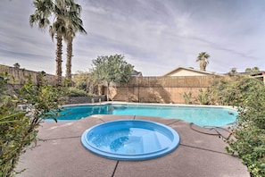 A backyard with a swimming pool, a hot tub, and a wooden fence.