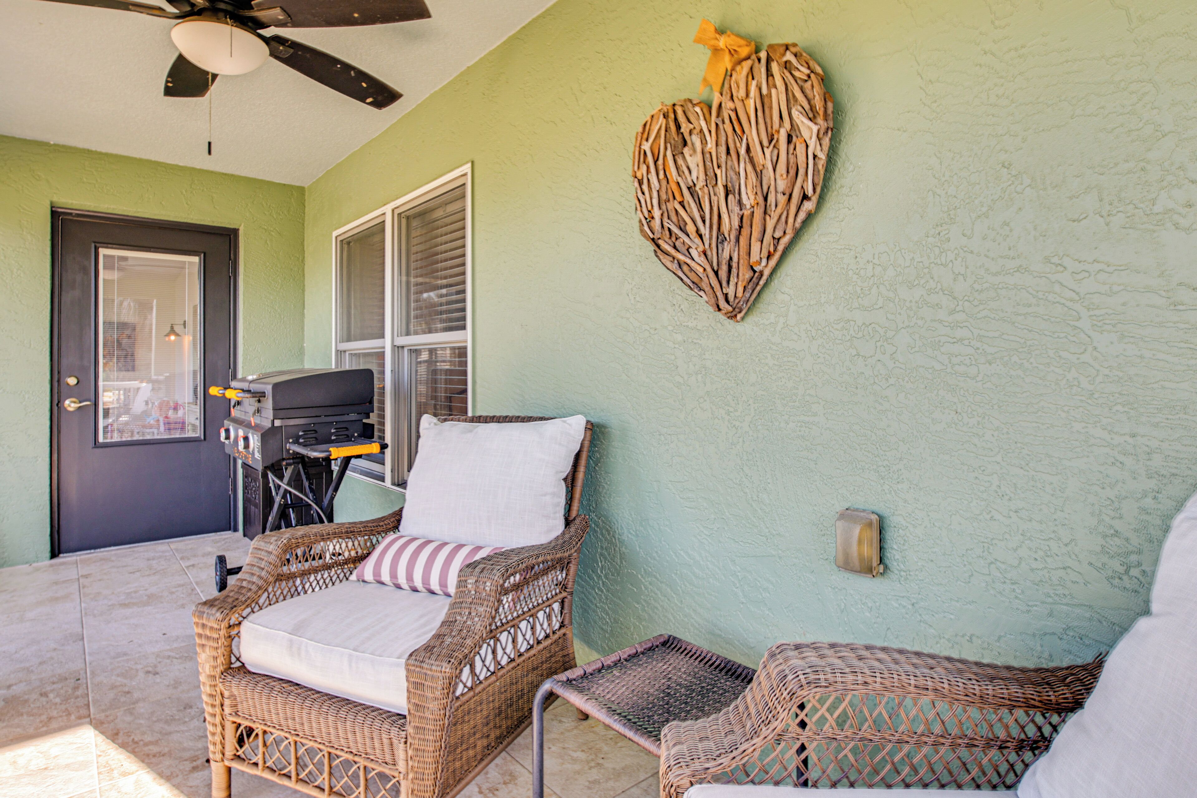 Un patio con mobiliario de mimbre, un ventilador de techo y una decoración con forma de corazón en la pared.