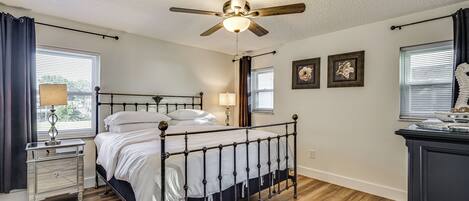 Une chambre Ă coucher comprenant un lit, une table de chevet, un ventilateur de plafond et une commode.