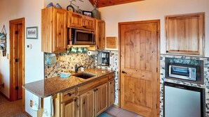Een keuken met houten kastjes, een inbouwmagnetron, een toasteroven en een betegelde achterwand.