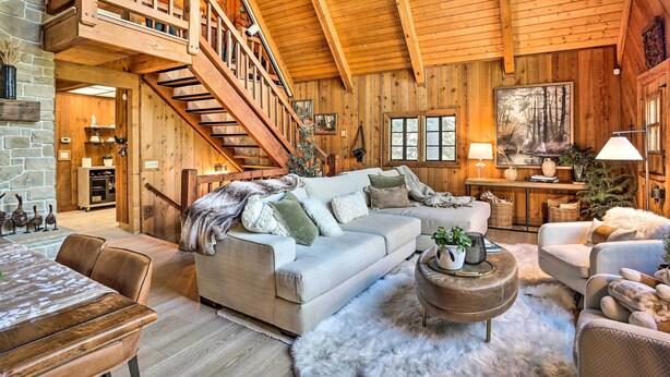 A spacious living room with a high ceiling, wooden beams, a staircase, and a cozy fireplace. - Cimarron Lodge Retreat With 3 Decks & Grill! (Cedar Glen)