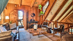 A cozy wooden interior with a leather sofa, a piano, and a dining table with a candle. - Cimarron Lodge Retreat With 3 Decks & Grill! (Cedar Glen)
