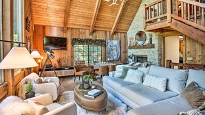 A cozy log cabin interior with a stone fireplace, a television, and a dining area. - Cimarron Lodge Retreat With 3 Decks & Grill! (Cedar Glen)