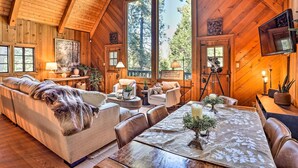 A cozy log cabin interior with a large dining table, leather sofas, and a television mounted on the wall. - Cimarron Lodge Retreat With 3 Decks & Grill! (Cedar Glen)