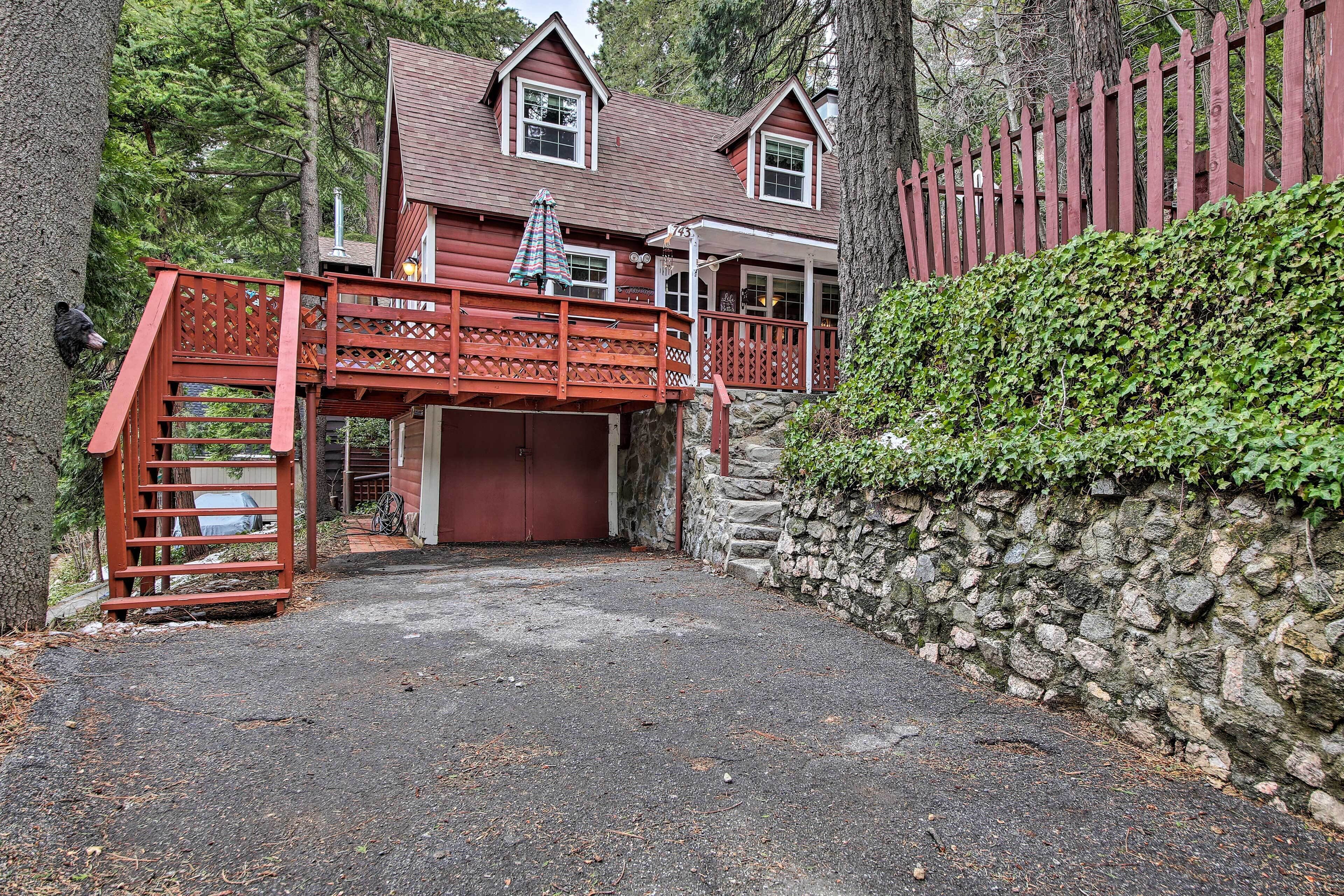 A two-story wooden house with a red balcony and a stone wall.