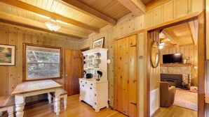 Un interior de madera con una mesa de comedor, armarios blancos, una chimenea y un televisor.