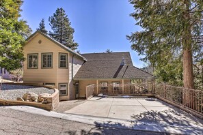A two-story house with a covered porch, a stone retaining wall, and a large tree in the background. - Huge Lake Arrowhead Home w/ 3 Decks & Grill! (Lake Arrowhead)