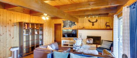 A cozy cabin interior with a wooden interior, a fireplace, leather furniture, and a mounted deer head.