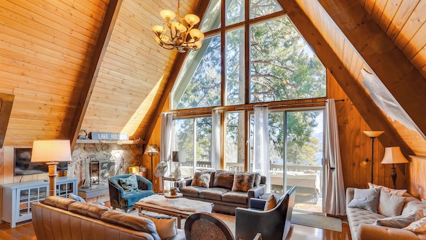 A spacious loft with a high ceiling, large windows, and a cozy seating area with leather sofas and chairs. - A-frame Home w/ 3 Decks & Lake Arrowhead Views! (Lake Arrowhead)