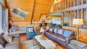 A spacious living area with a high ceiling, wooden walls, and a staircase. - A-frame Home w/ 3 Decks & Lake Arrowhead Views! (Lake Arrowhead)