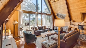 A cozy loft-style living room with a high ceiling, large windows, and a fireplace. - A-frame Home w/ 3 Decks & Lake Arrowhead Views! (Lake Arrowhead)