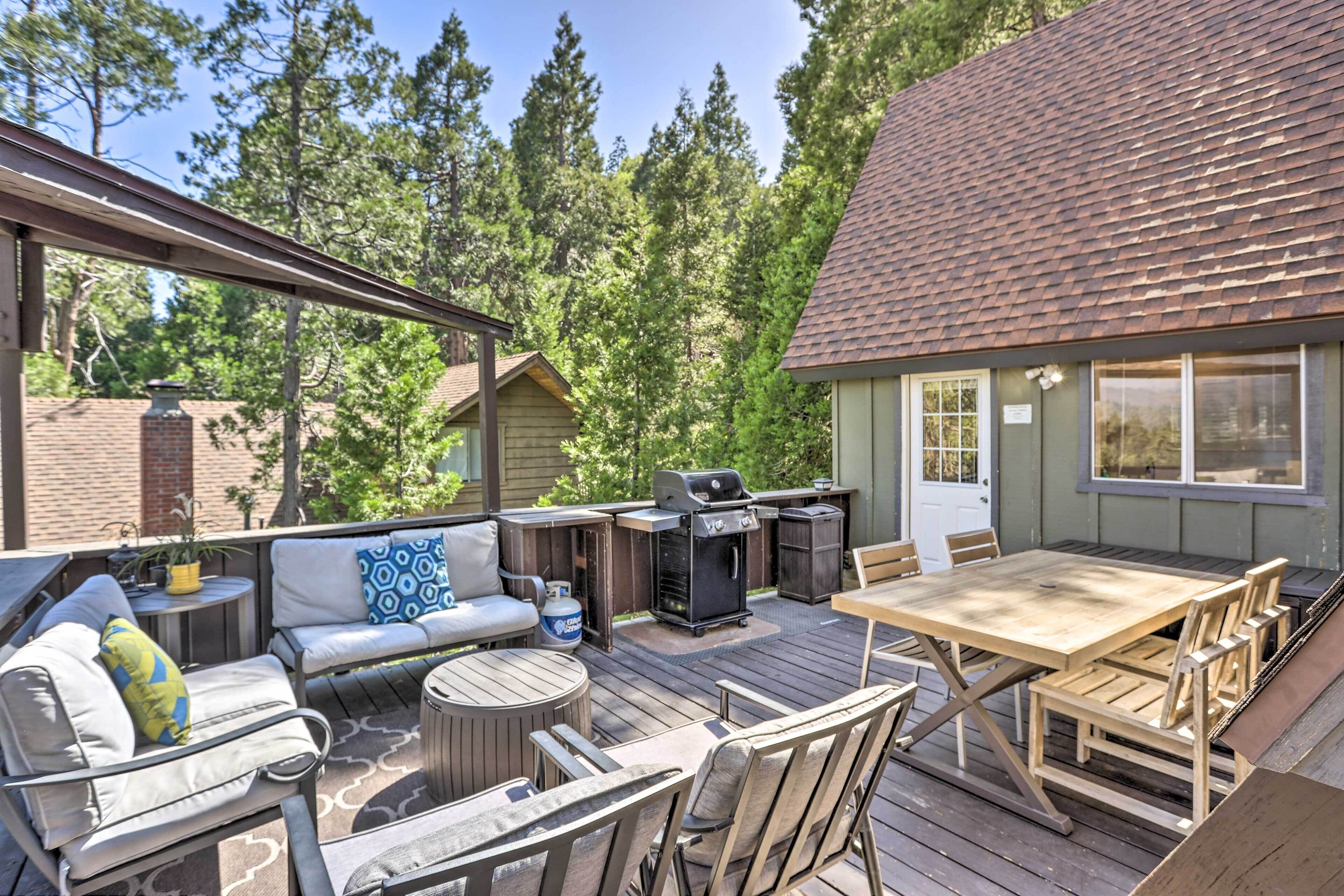 An outdoor deck with a dining table, chairs, a grill, and a sofa.