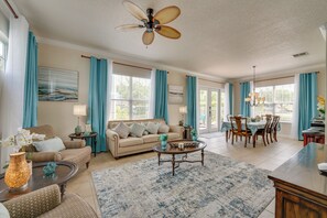 A spacious living room with a beige sofa, a coffee table, and a dining area with a table and chairs.