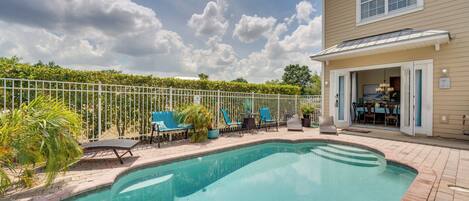 A swimming pool with lounge chairs and a covered patio area.