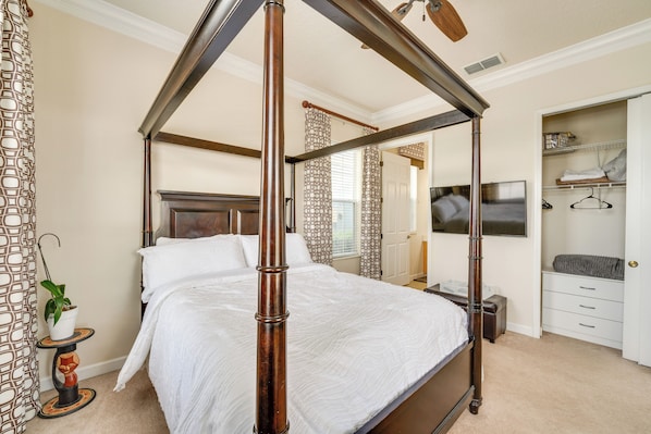 A four-poster bed in a bedroom with a wooden headboard, a bedside table, and a closet with hanging space.