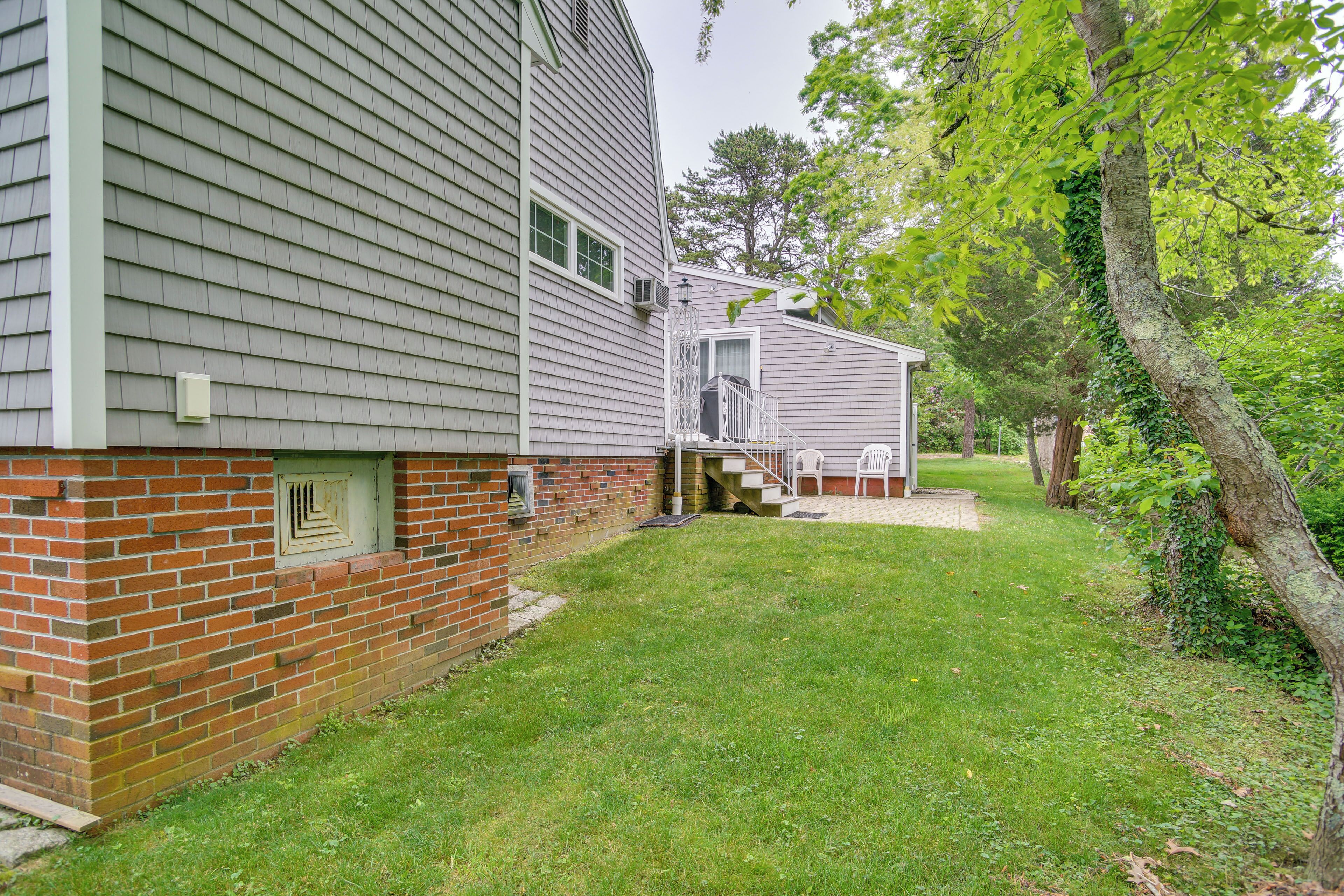A two-story house with a brick foundation and a grey siding exterior.