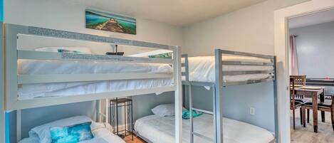 Habitación con literas, un escritorio, una silla, un cuadro en la pared y suelo de madera.