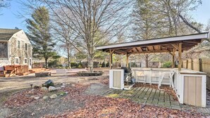 Un giardino con un'area barbecue coperta, un edificio in pietra e un molo in legno.