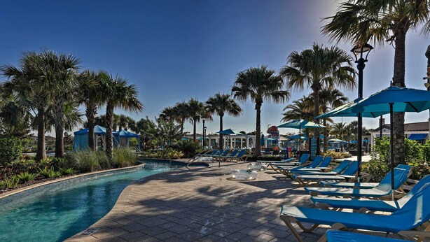 A poolside area with lounge chairs and umbrellas, surrounded by palm trees and a clear blue sky. - 3 Mi to Disney: Family-friendly Home w/ Pool (Kissimmee)