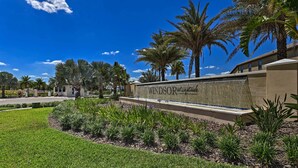 A landscaped entrance with a sign reading "Windsor & Schaefer," palm trees, and a clear blue sky. - 3 Mi to Disney: Family-friendly Home w/ Pool (Kissimmee)