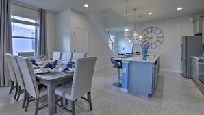 A modern kitchen with a central island, a dining area with a large table and chairs, and a staircase leading to an upper level. - 3 Mi to Disney: Family-friendly Home w/ Pool (Kissimmee)