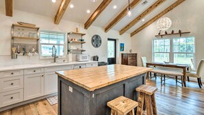 A spacious kitchen with a large island, wooden beams, and a dining area with a view. - Trendy Palm City Cottage w/ Porch on 5 Acres! (Palm City)