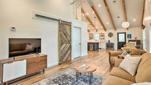 A spacious living room with a large TV, wooden furniture, and a ceiling fan. - Trendy Palm City Cottage w/ Porch on 5 Acres! (Palm City)