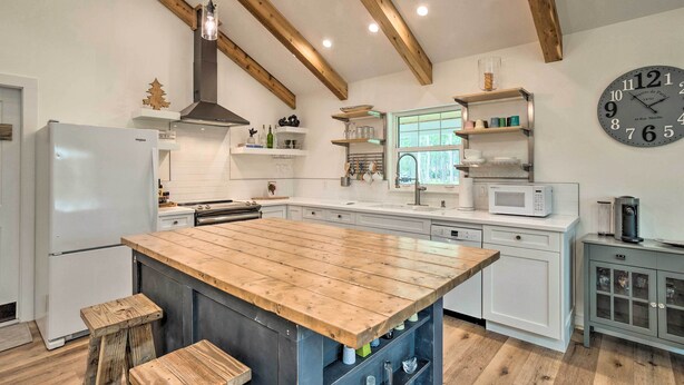 A kitchen with a wooden island, white cabinets, a built-in microwave, and a clock on the wall. - Trendy Palm City Cottage w/ Porch on 5 Acres! (Palm City)
