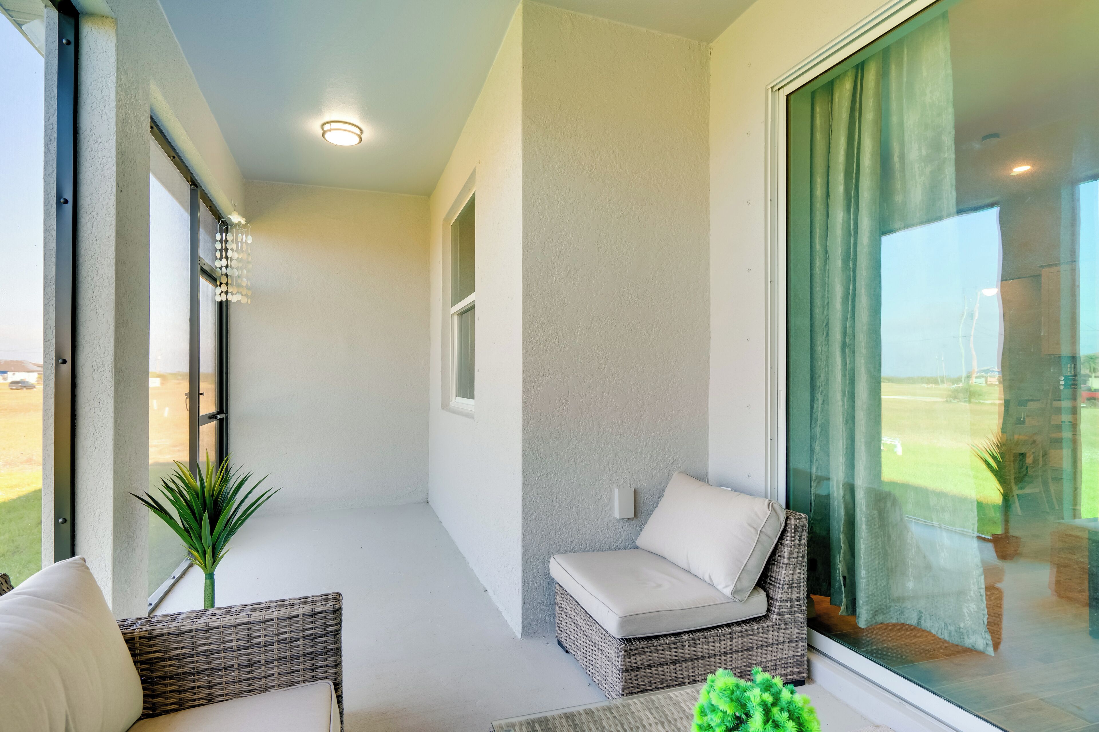 A balcony with wicker furniture, a cushion, and a potted plant.