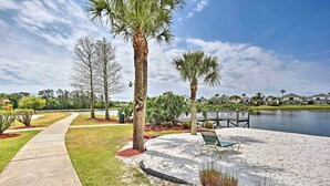 A waterfront park with a walking path, palm trees, a bench, and a view of houses across the water. - Patio + Pool Access: Townhome < 9 Mi to Disney! (Kissimmee)
