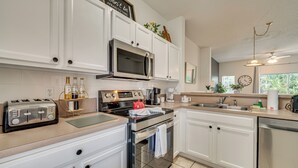 A modern kitchen with white cabinets, stainless steel appliances, and a built-in oven. - Patio + Pool Access: Townhome < 9 Mi to Disney! (Kissimmee)