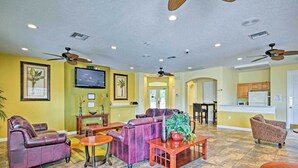 A spacious living area with a purple sofa, wooden coffee table, and ceiling fans. - Patio + Pool Access: Townhome < 9 Mi to Disney! (Kissimmee)
