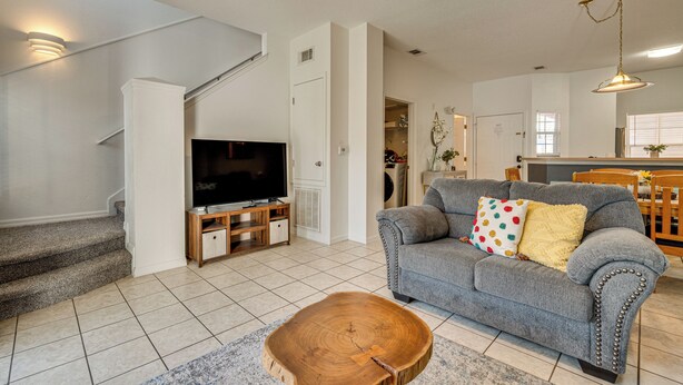 A living room with a grey sofa, a wooden coffee table, and a flat-screen TV on a wooden stand. - Patio + Pool Access: Townhome < 9 Mi to Disney! (Kissimmee)