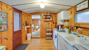 A wooden cabin interior with a kitchen, a dining area, and a bathroom. - Rustic Berkshires Cottage at Lake Buel w/ Kayaks! (Great Barrington)