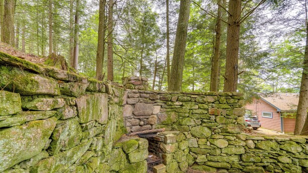 A stone structure in a forested area with a house in the background. - Rustic Berkshires Cottage at Lake Buel w/ Kayaks! (Great Barrington)