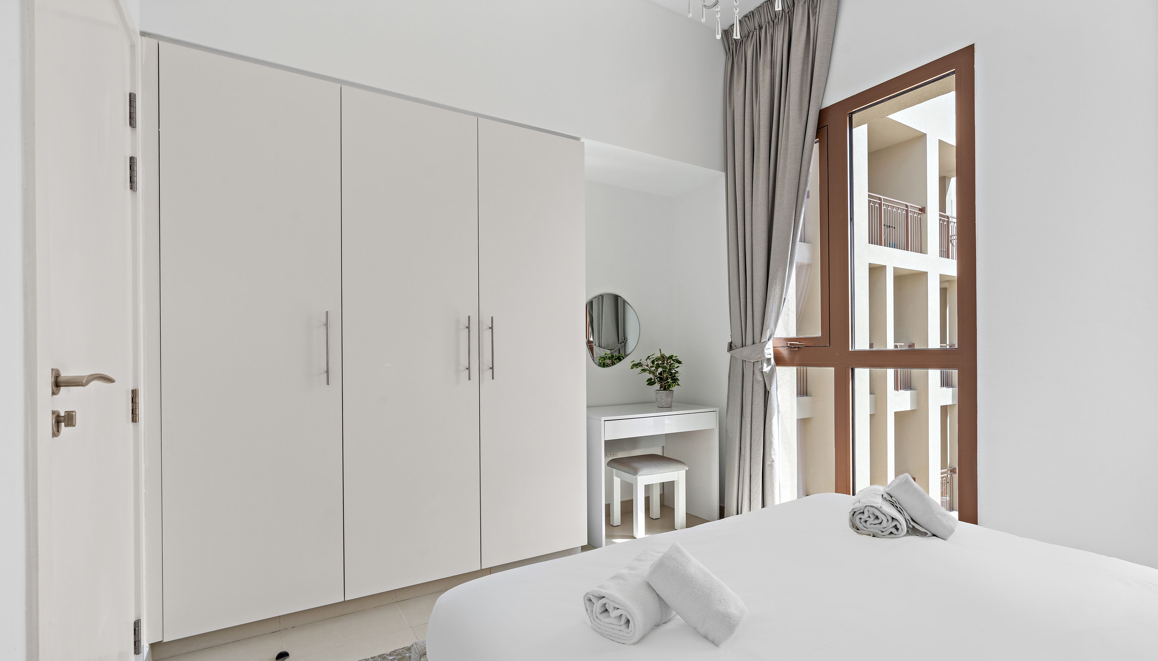 A bedroom with a bed, a desk, a chair, and a wardrobe.