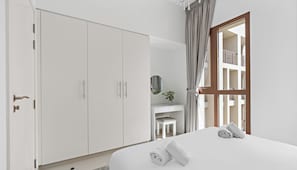 A bedroom with a bed, a desk, a chair, and a wardrobe.