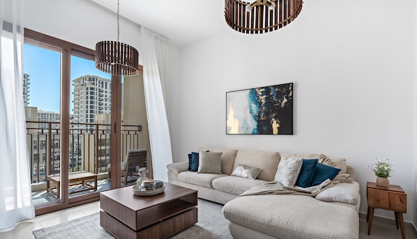A modern living room with a large window, a sofa, a coffee table, and a painting on the wall.
