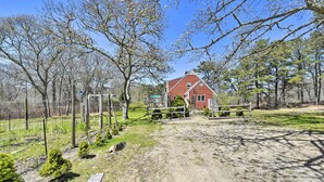 A rural property with a red barn, fenced areas, and sparse vegetation. - Peaceful Chilmark Farmhouse by Menemsha Beach (Chilmark)