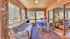 A wooden deck with a blue table and chairs, a sofa, and a view of the outdoors. - Peaceful Chilmark Farmhouse by Menemsha Beach (Chilmark)
