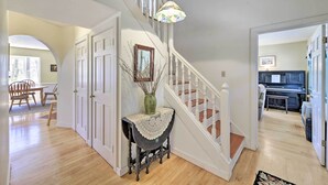 A spacious living area with a staircase, a dining area, and a kitchen visible in the background. - Peaceful Chilmark Farmhouse by Menemsha Beach (Chilmark)
