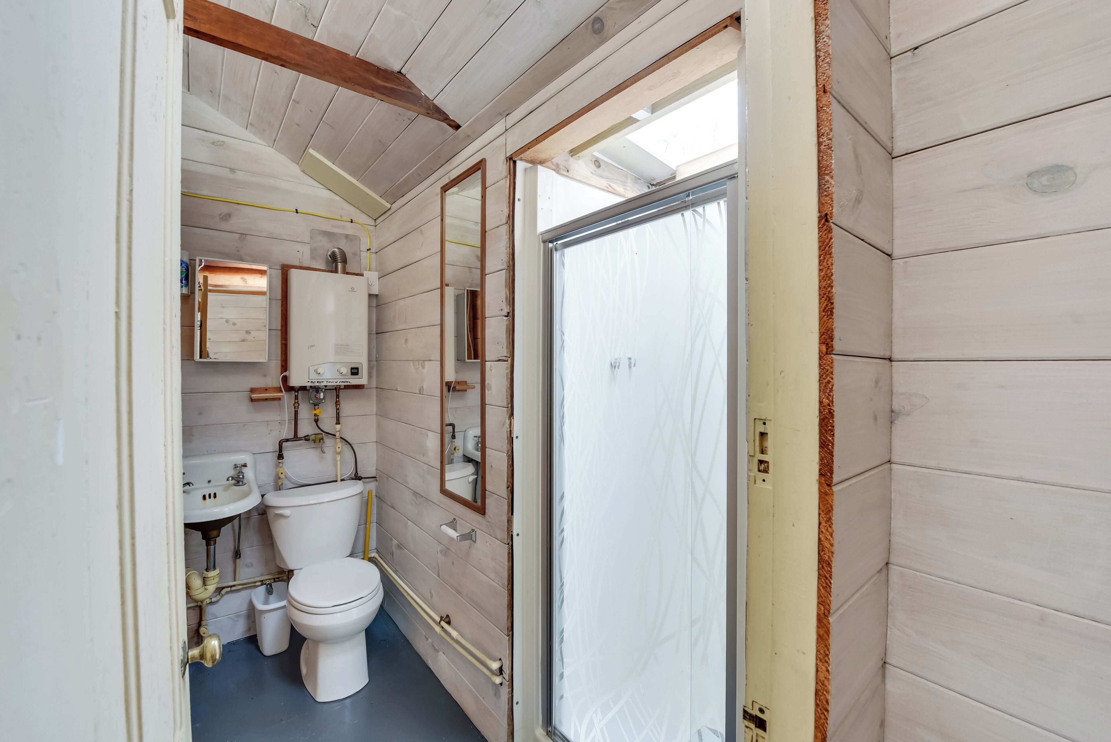 A compact bathroom with a toilet, sink, and mirror.