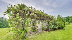 Une petite cabane rustique, avec des fondations en pierre et une structure en bois recouverte de plantes grimpantes.