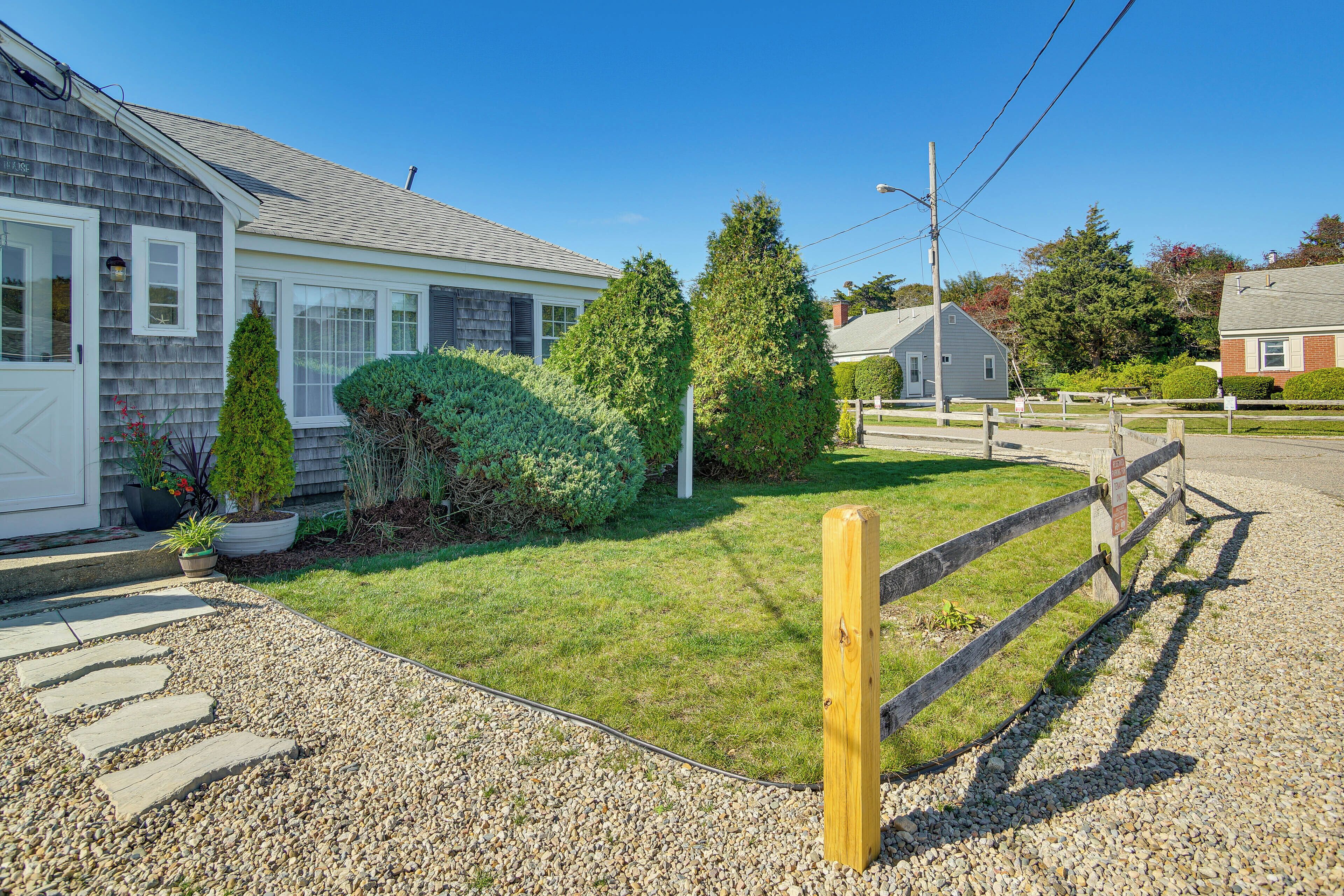 A residential property with a well-maintained lawn, a gravel pathway, and a wooden fence.