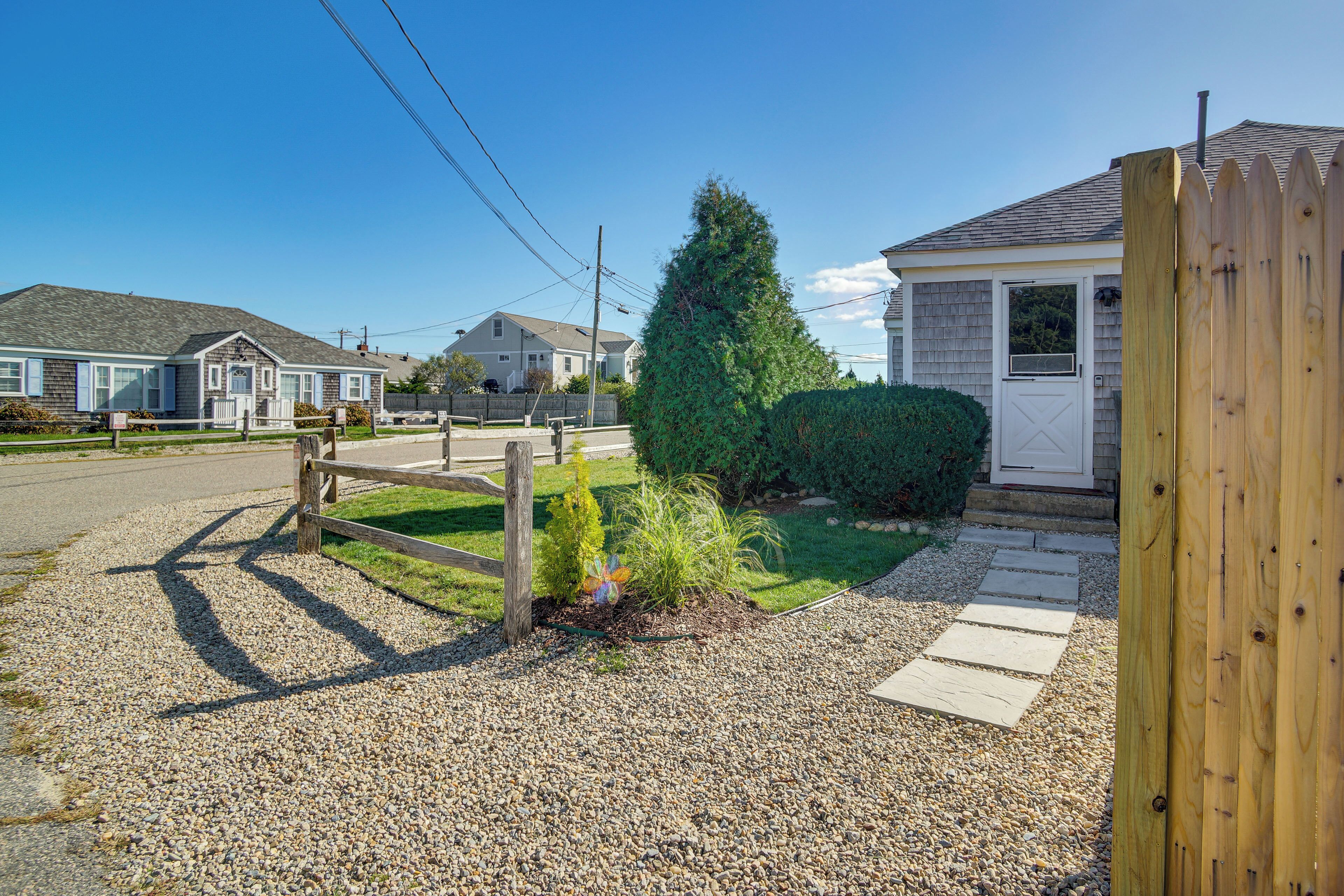 A residential street with houses, a wooden fence, and a gravel driveway.