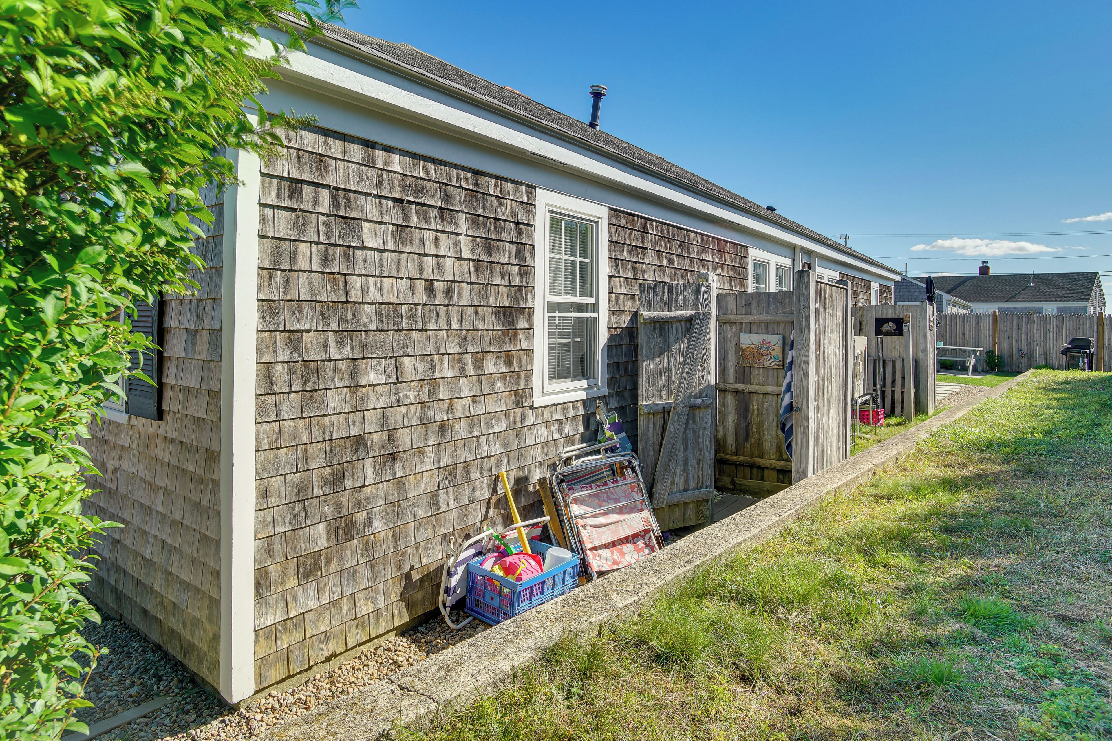 A single-story house with a shingled exterior, a front door, and a small porch area with a wooden fence.