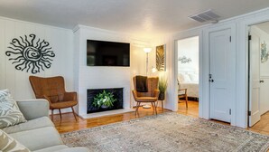 En stue med pejs, sofa, lænestol og et tæppe.