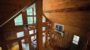 A wooden cabin with a loft bedroom, a fireplace, and a TV. - Cozy waterfront house in quiet neighborhood! (Jasper)
